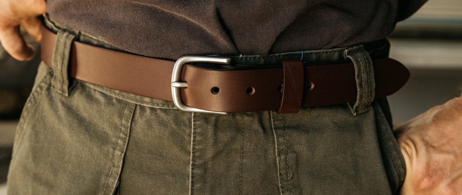 A cognac classic belt around a man's pants.