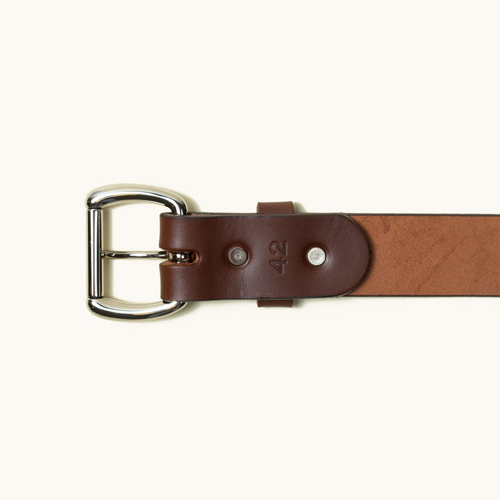 The bottom half of a Cognac Standard belt showing a stainless roller ball buckle and two stainless rivets.