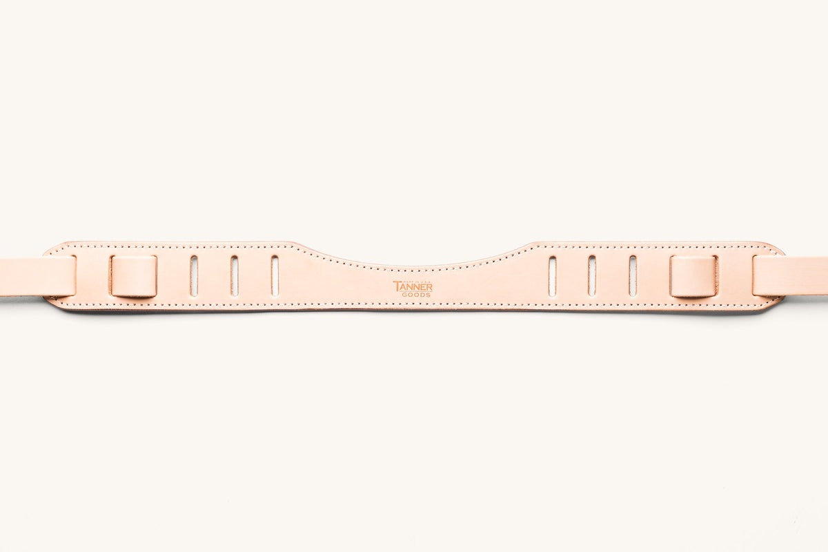 A natural SLR strap focusing on the shoulder piece with "Tanner Goods" stamped into the leather.