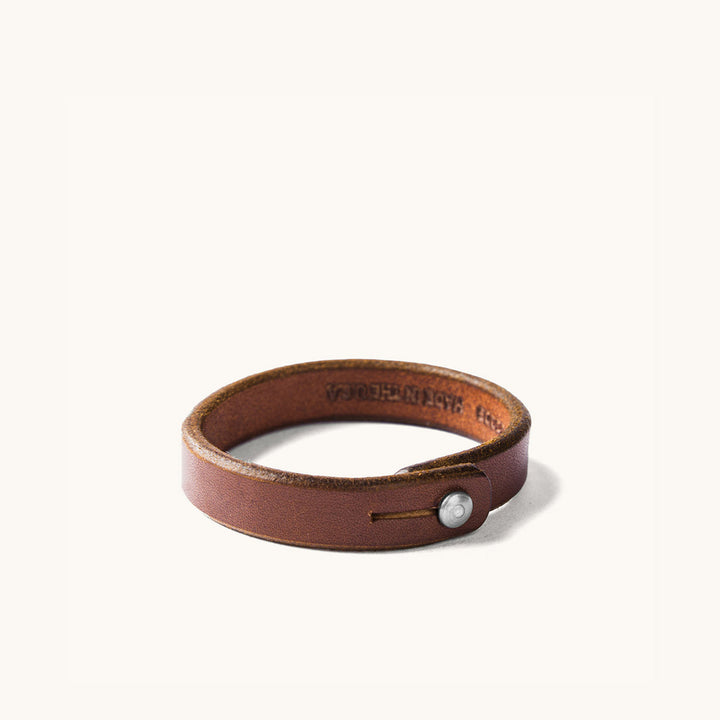Brown leather wristband with metal rivet closure.