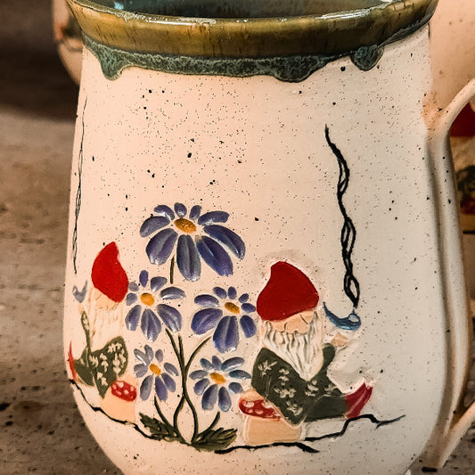 Ceramic mug with floral and gnome design on a textured surface