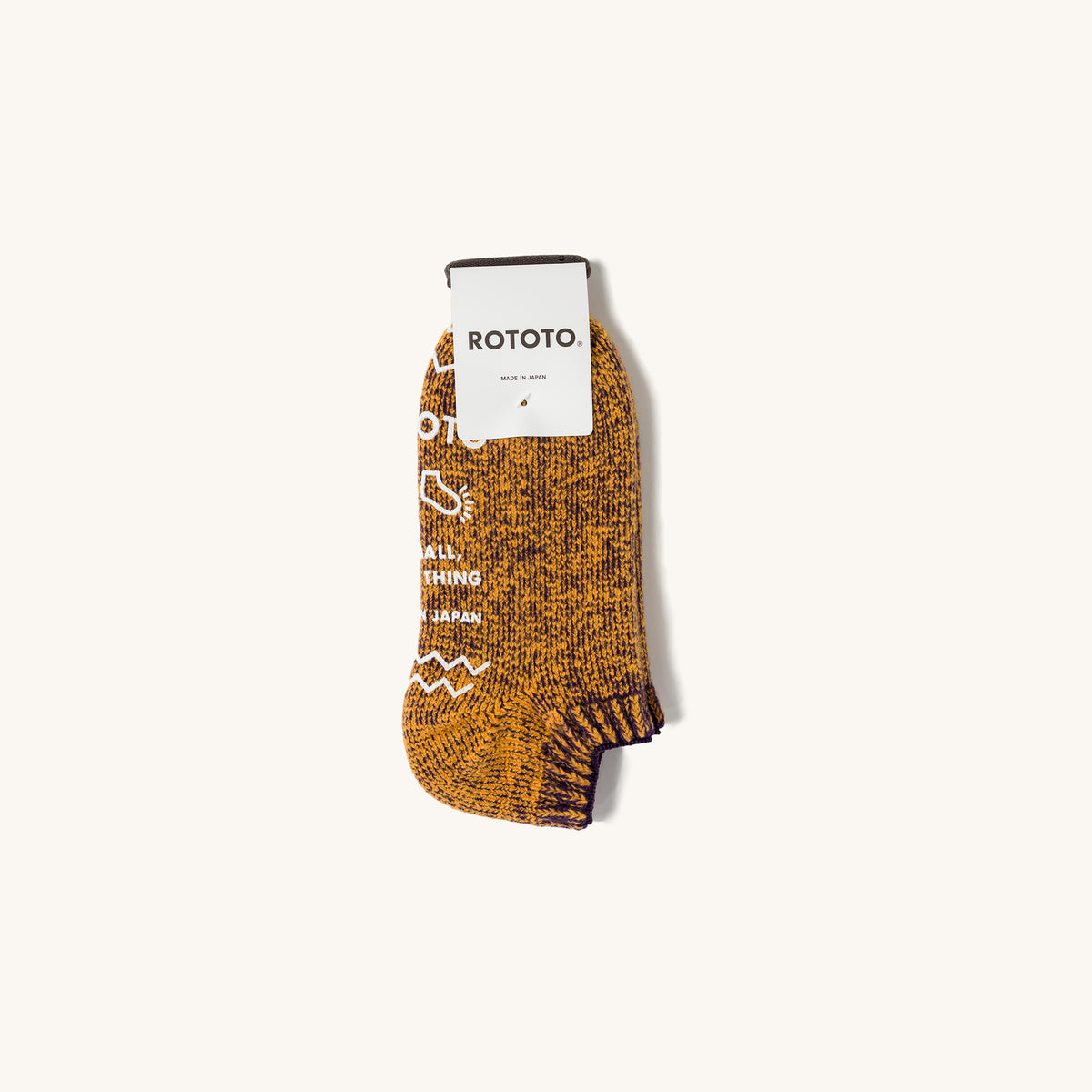 Orange pile sock slipper by Rototo with blueberry marled knit and white graphic text on cream background.