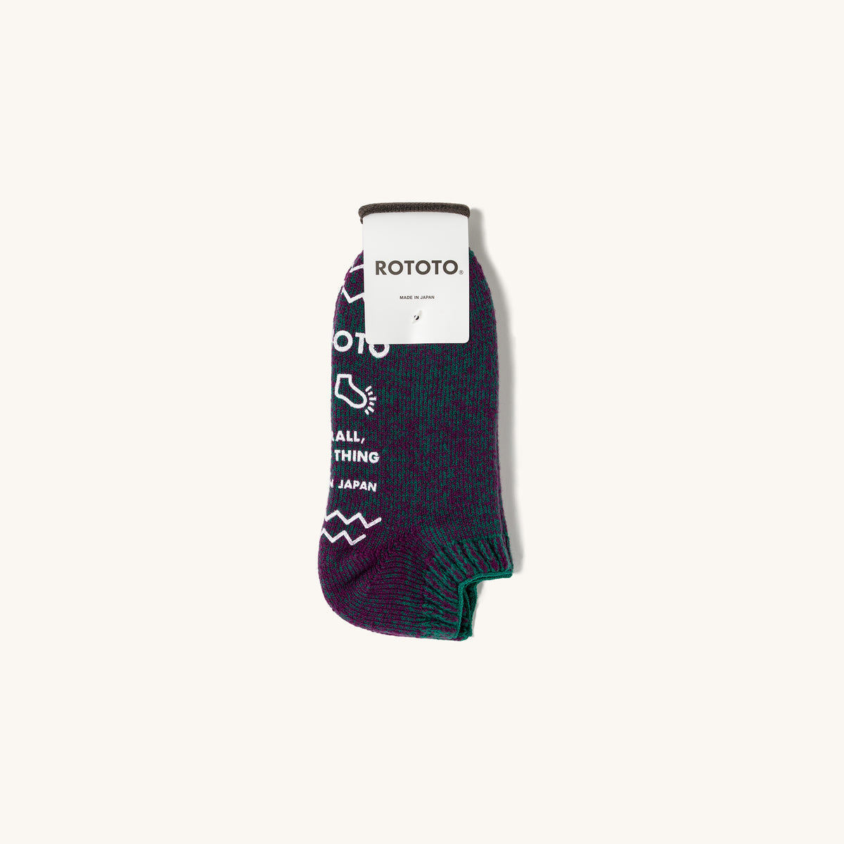Purple and green pile sock slipper by Rototo with white text and zigzag knit pattern.