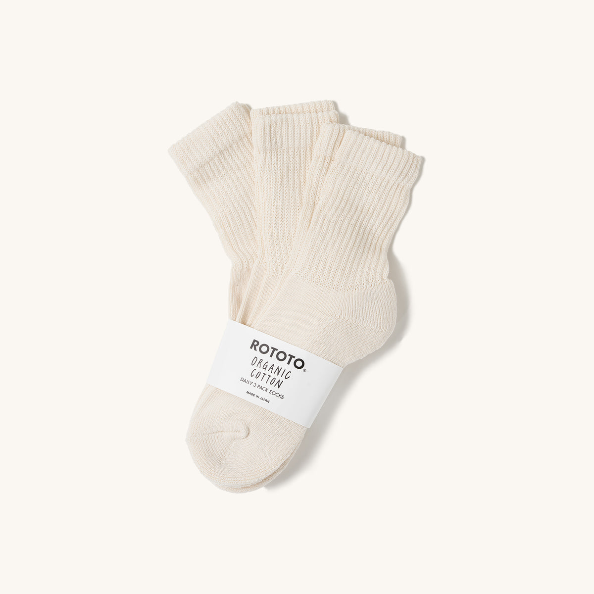 Ivory mini crew socks by Rototo, a 3-pack with ribbed cuffs and an organic cotton band on a cream background.