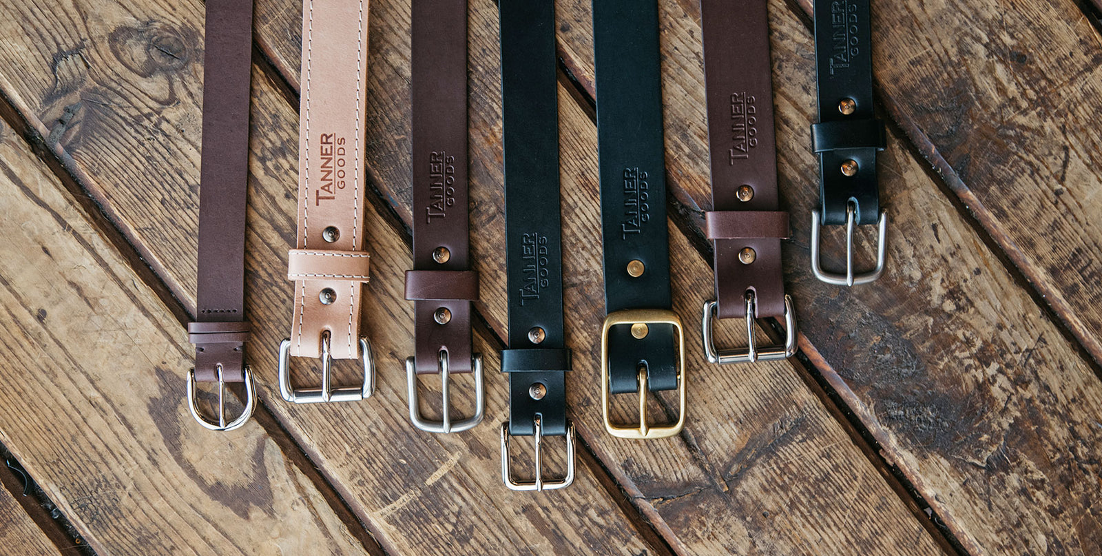 Multiple leather belts laying in a row.