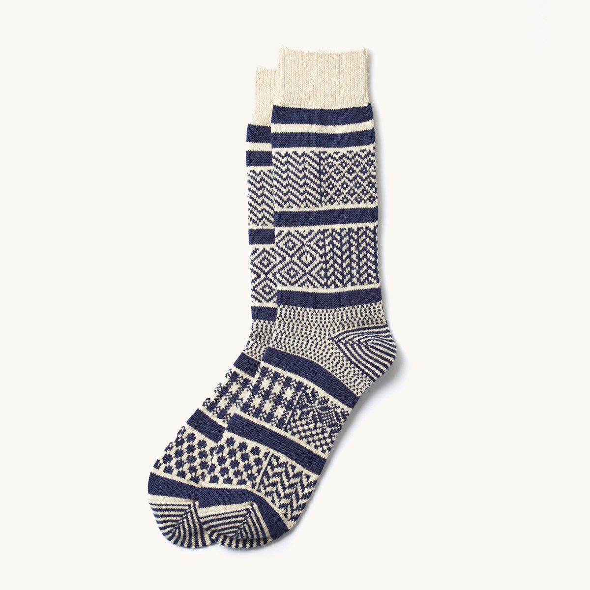 Pair of knitted ivory and navy multi jacquard crew socks with various geometric patterns, laid flat.