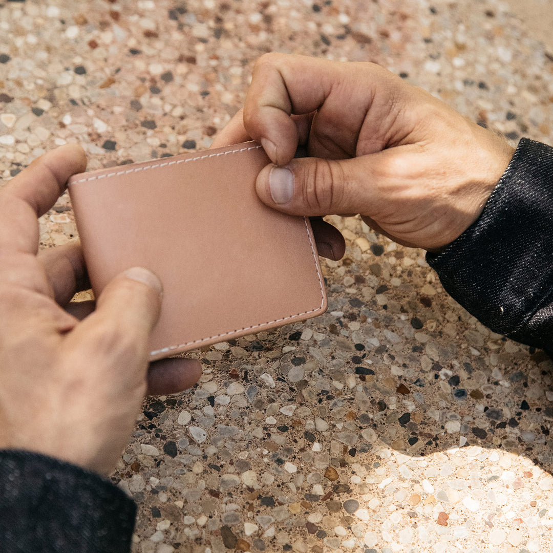 Rugged hands holding a closed Natural Utility Bifold.