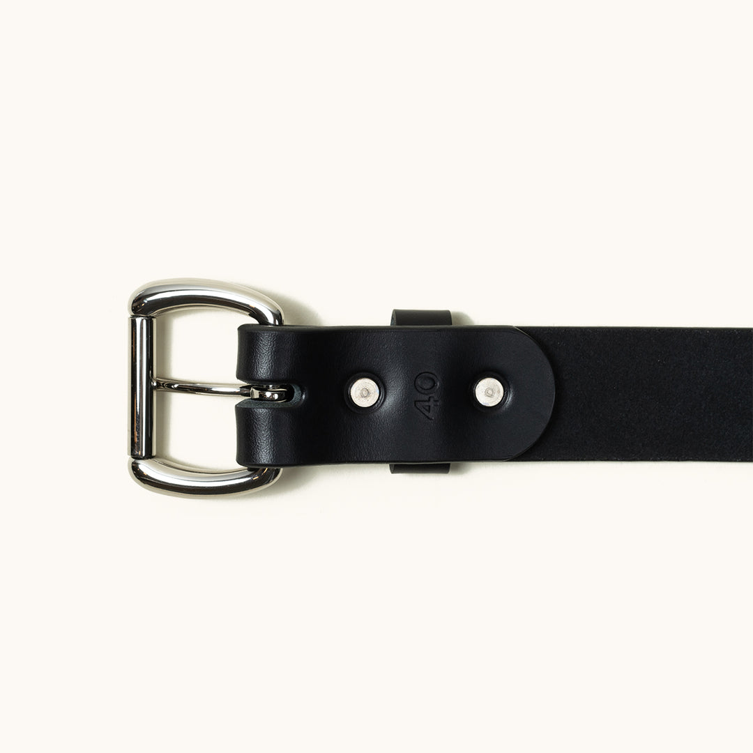 The bottom half of a black Standard belt showing a stainless roller ball buckle and two stainless rivets.