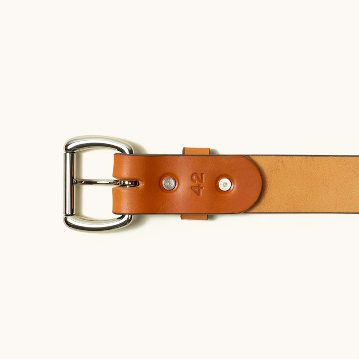 The bottom half of a Saddle Tan Standard belt showing a stainless roller ball buckle and two stainless rivets.