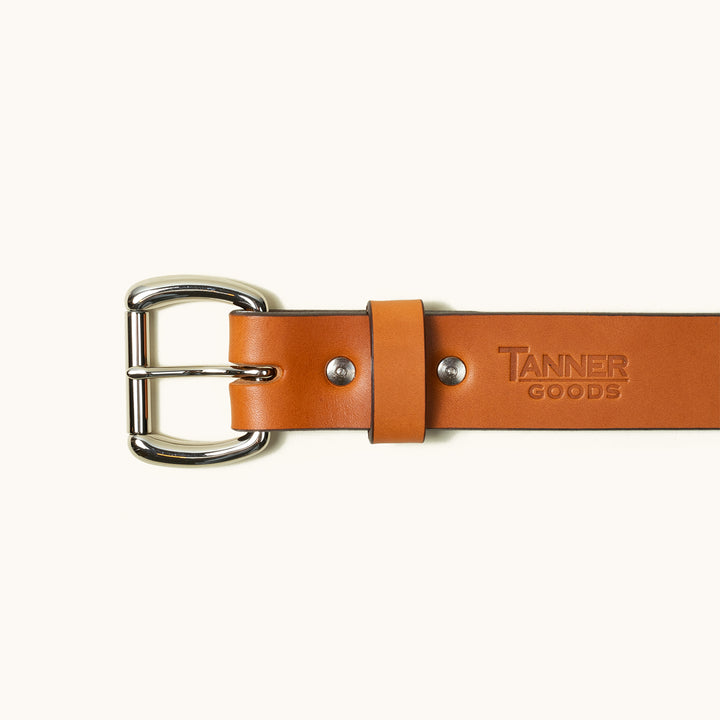 The top half of a Saddle Tan Standard belt showing a stainless roller ball buckle and Tanner Goods logo stamped into the belt.