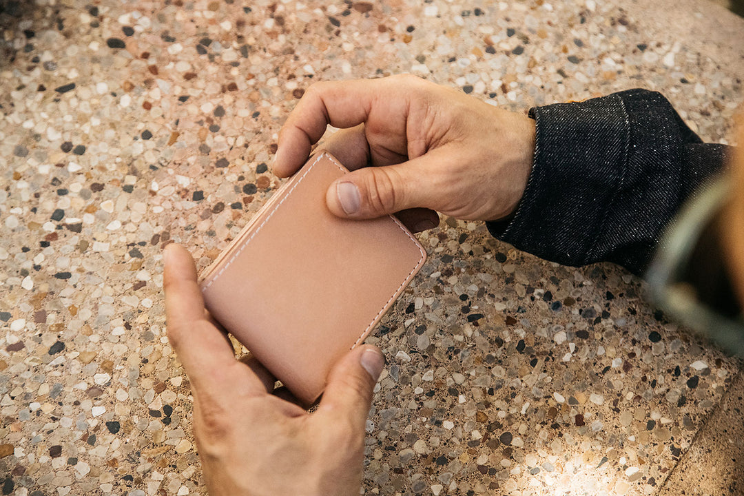 Hands holding a closed natural Utility Bifold.