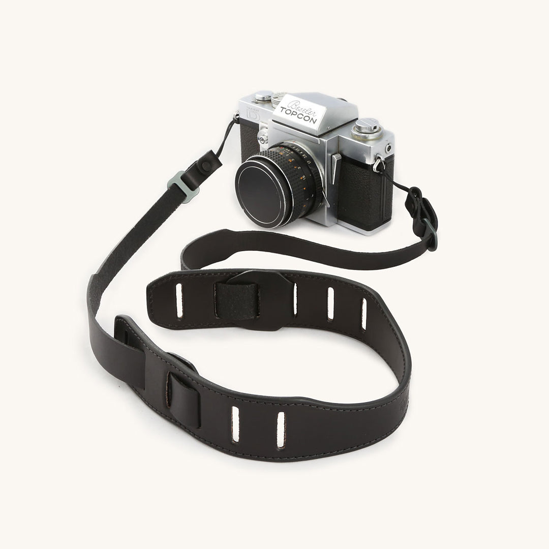 A silver and black SLR camera with a black leather strap.