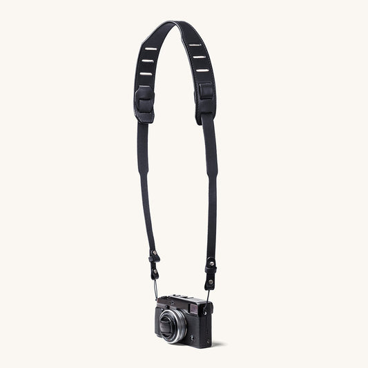 A silver and black SLR camera with a black leather strap.