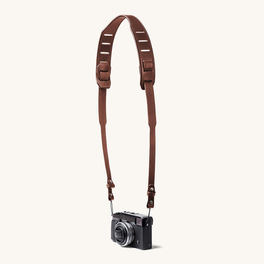 A silver and black SLR camera with a black leather strap.