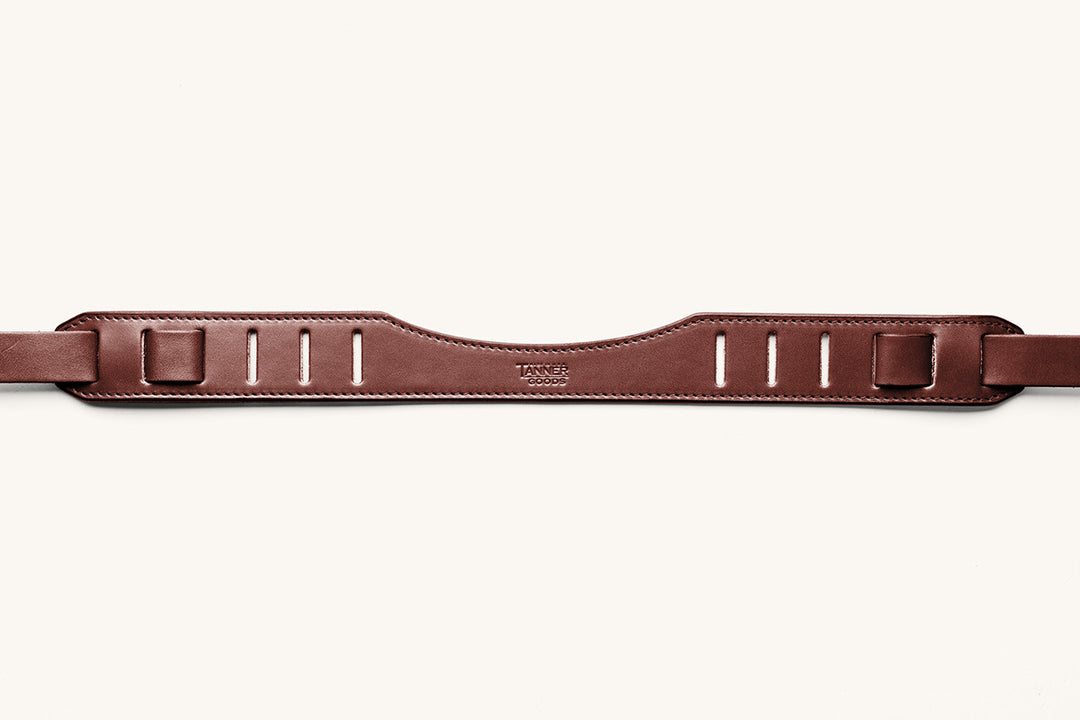 A cognac SLR strap focusing on the shoulder piece with "Tanner Goods" stamped into the leather.