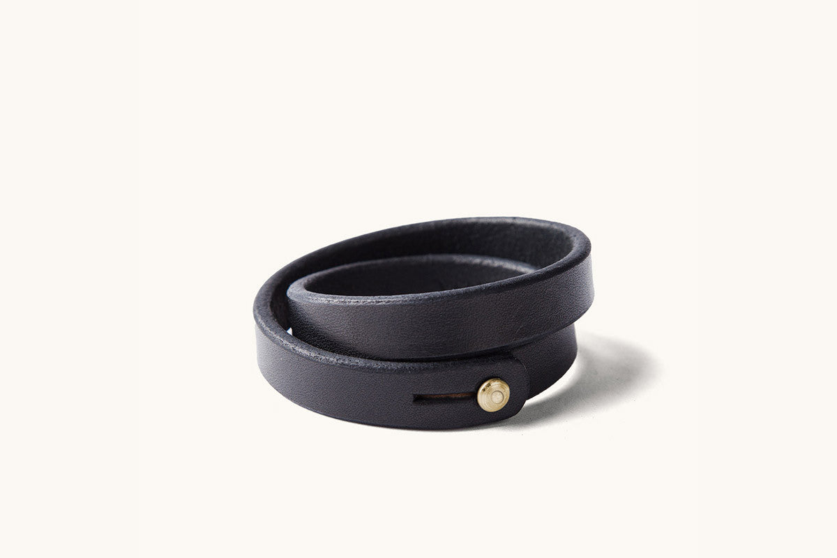 A double wrap black leather wristband with brass closure.