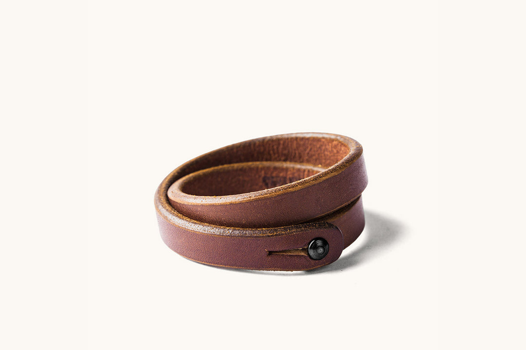 A double wrap brown leather wristband with black metal closure.