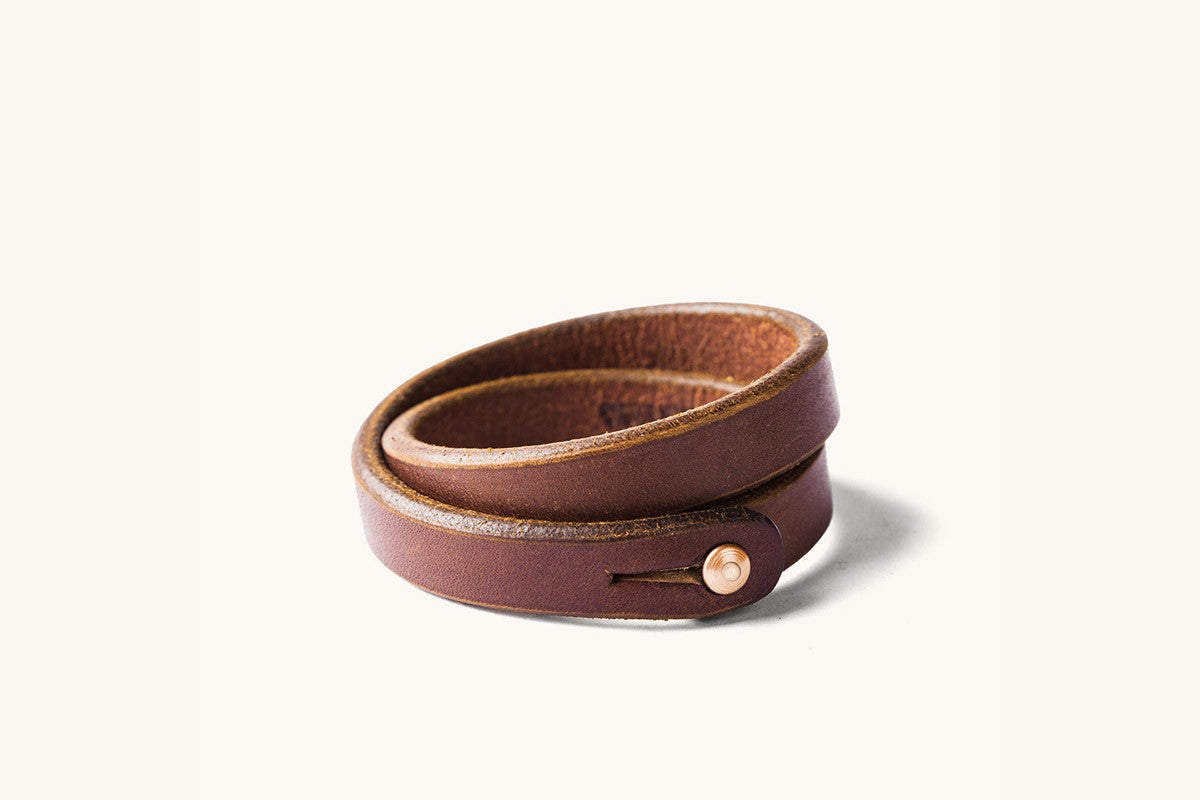 A double wrap brown leather wristband with copper closure.