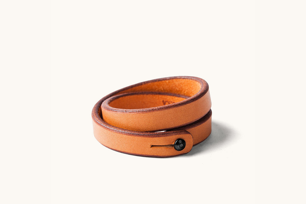 A double wrap tan leather wristband with black closure.
