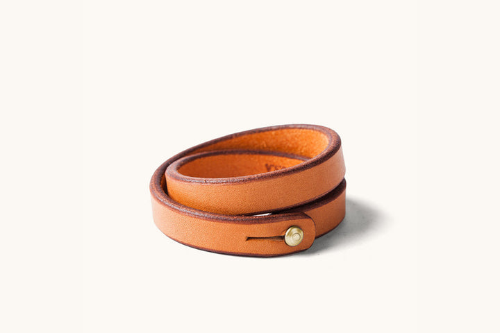 A double wrap tan leather wristband with brass closure.