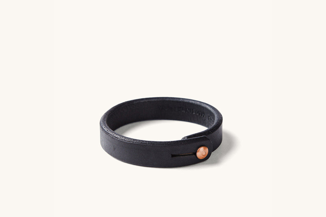 A black leather wristband with copper rivet closure.