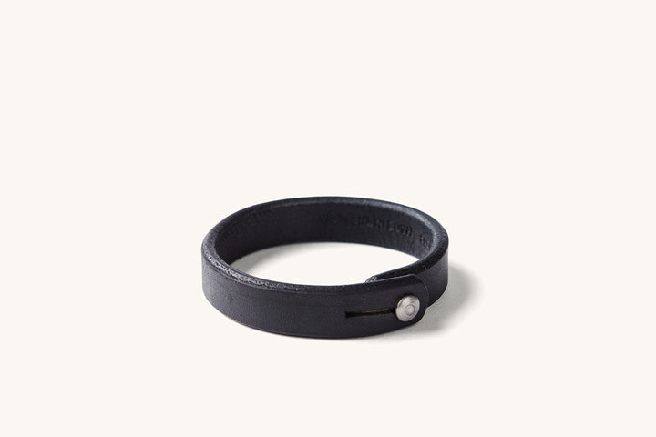 A black leather wristband with metal rivet closure.