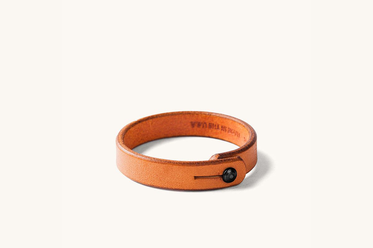 Tan leather wristband with black rivet closure.