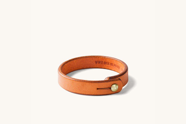 Tan leather wristband with brass rivet closure.