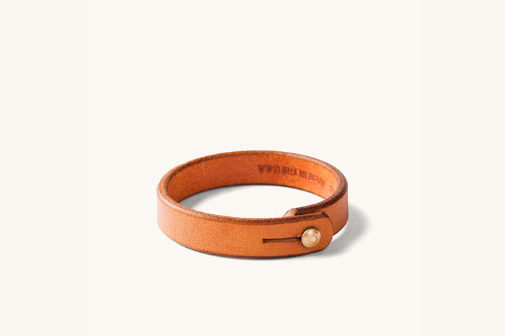 Tan leather wristband with copper rivet closure.