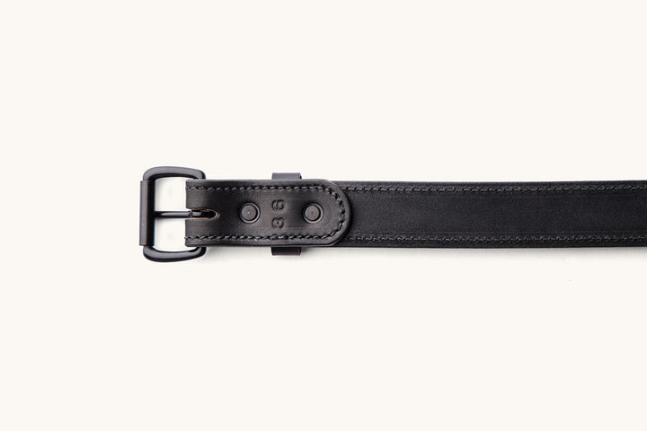 the underside of a black leather belt with black hardware