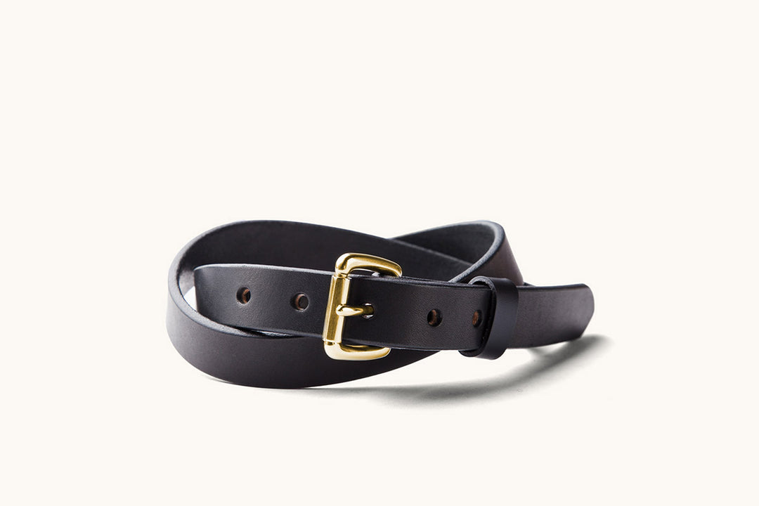 a skinny black leather belt with brass roller buckle