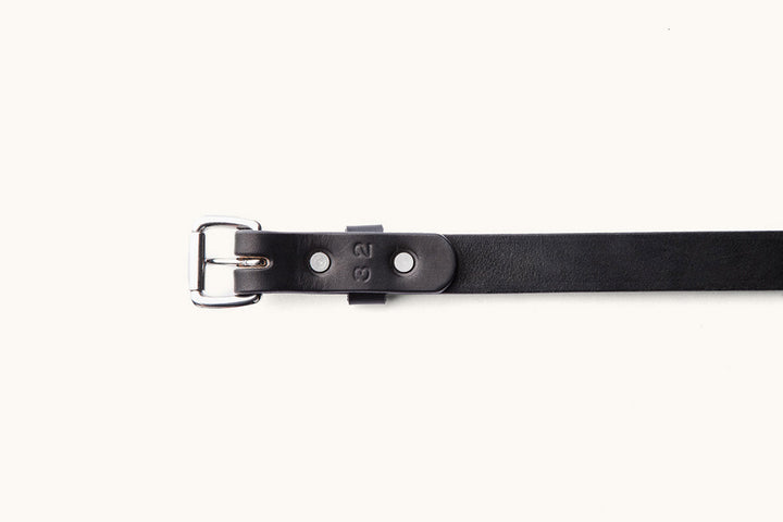 the underside of a black leather belt, size 32, with silver hardware
