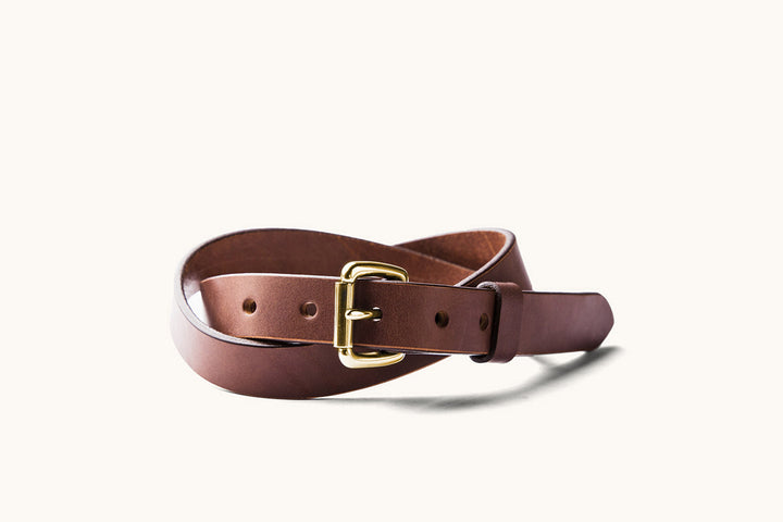 a skinny brown leather belt with brass roller buckle