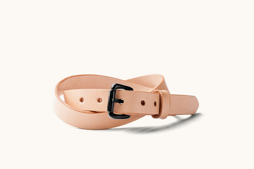 a narrow, sand colored leather belt with black roller buckle