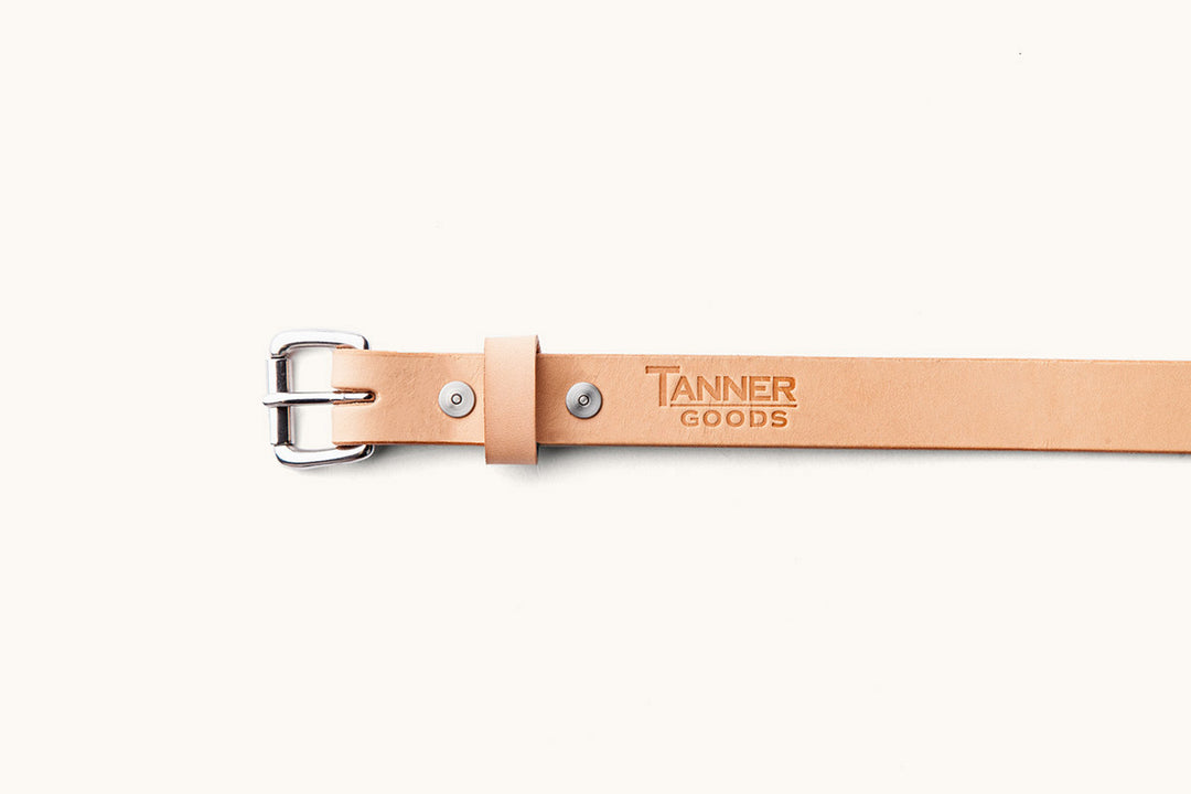 the frontside of a sand colored leather belt with Tanner Goods logo monogram
