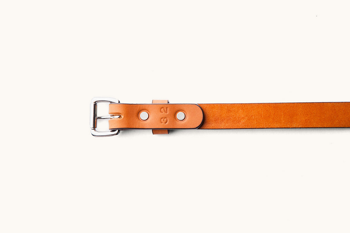The underside of a saddle tan belt, size 32, with silver hardware
