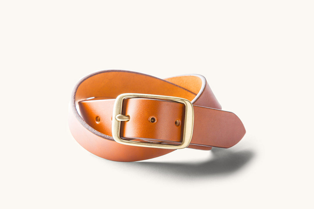 a tan leather belt with a cast brass buckle